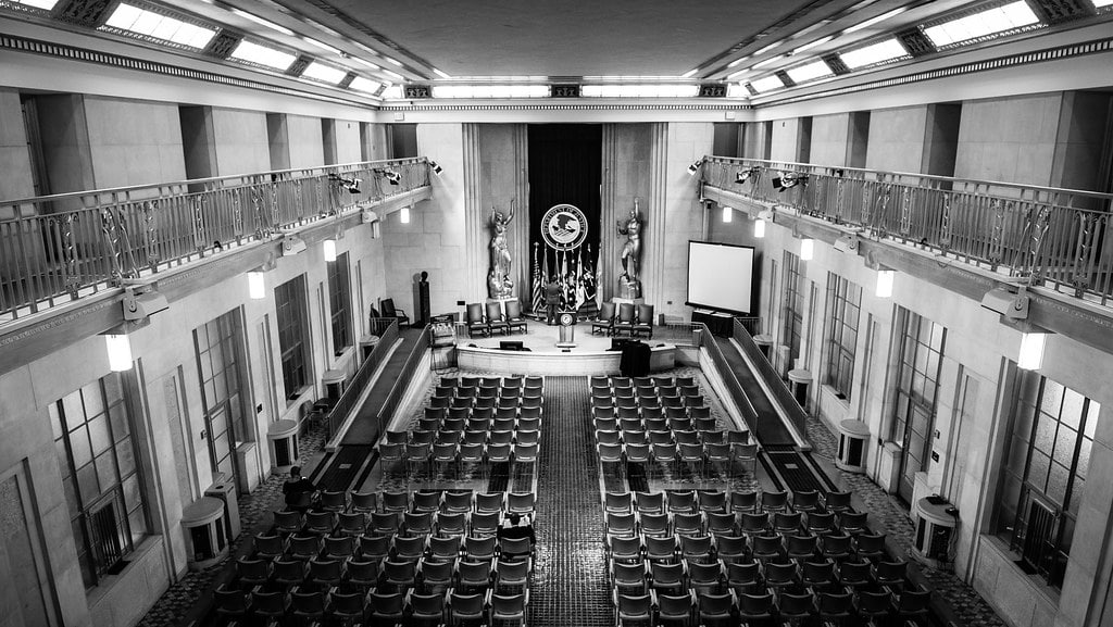 A black-and-white photo of an empty hall of chairs with a podium set up for the signing of the Fair Housing Act.