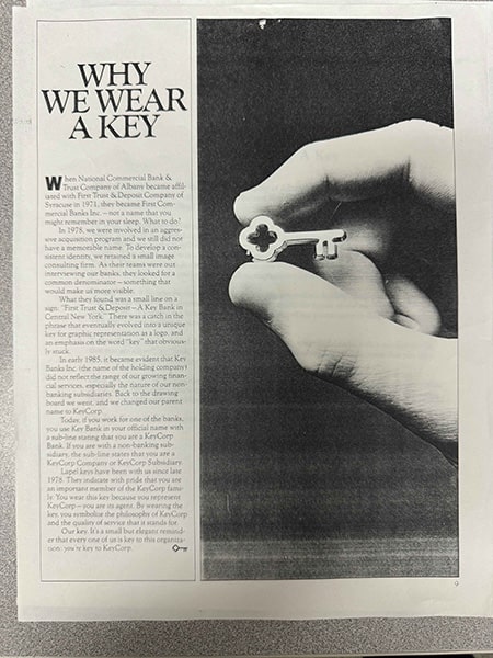 A picture of a black-and-white news article titled 'Why we wear a key.' On the right of the article is a hand holding a key in the shape of the KeyBank logo.