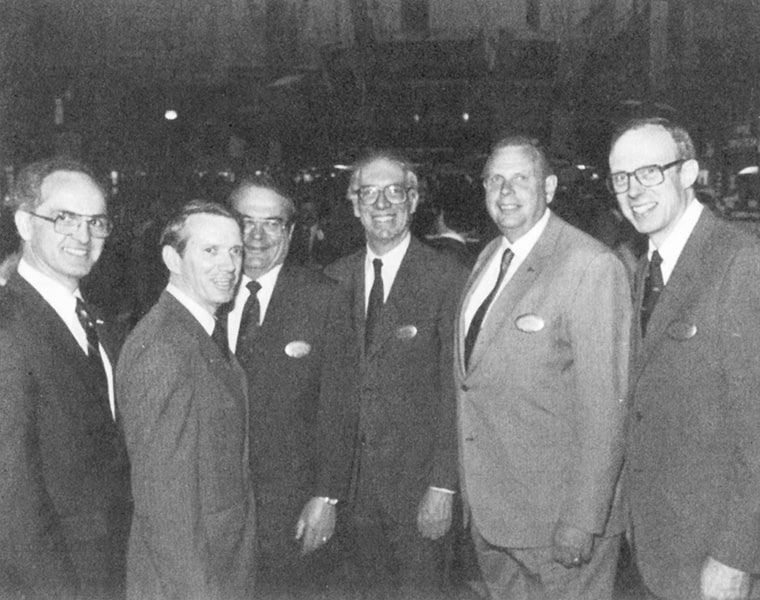 A black-and-white image of six men in suits standing at the entrance of the New York Stock Exchange.