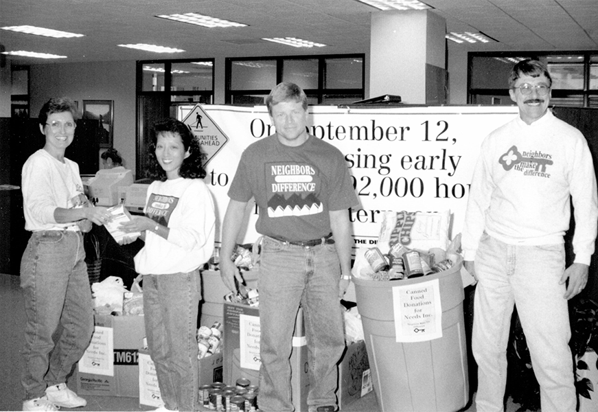 A black-and-white photograph of KeyBank volunteers with canned goods in a bin.