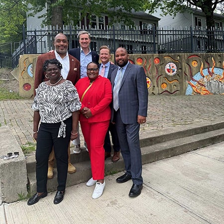 A colored photograph of Christopher M. Gorman with a group of people within a suburb.